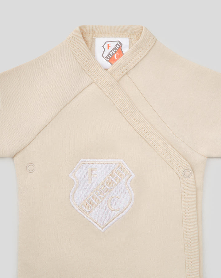 Beige baby romper close-up featuring FC Utrecht shield logo on the chest