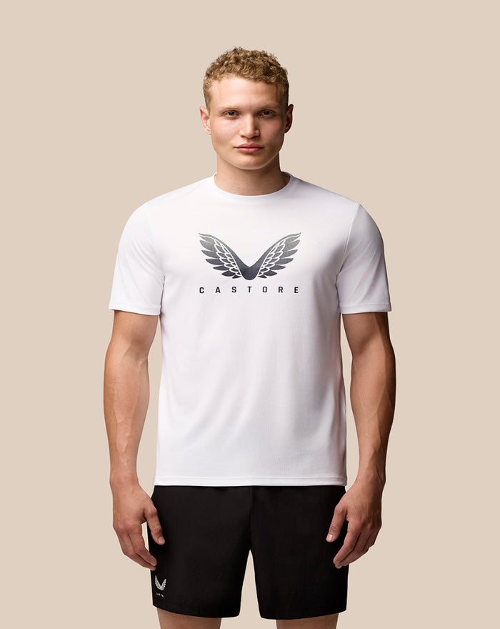Male model wearing a white Adapt Short Sleeve Graphic T Shirt with Castore wings logo on the chest.