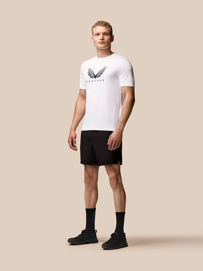 Man wearing white short sleeve graphic T shirt with wing logo on the chest and Castore branding