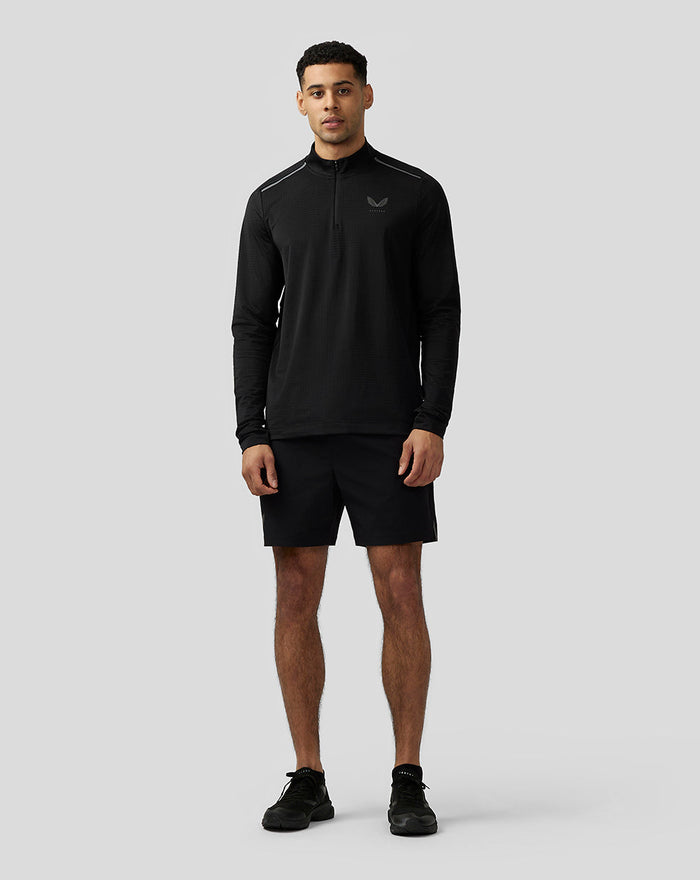 Male model wearing black Apex Aeromesh Kwartrits Top with funnel neck, front zip and reflective Castore logo on the chest.