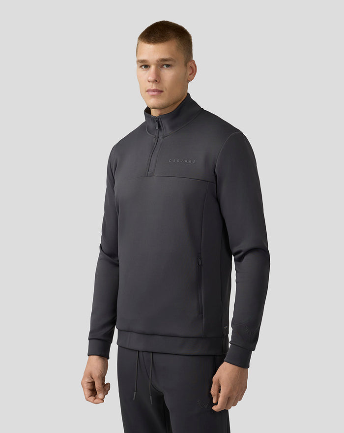Man draagt donkergrijze Scuba Top met kwart ritssluiting en zakken met rits, Castore logo op borst.