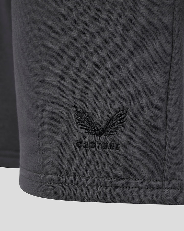 Close-up of the bottom hem showing the Castore wing logo on dark gray fleece shorts.