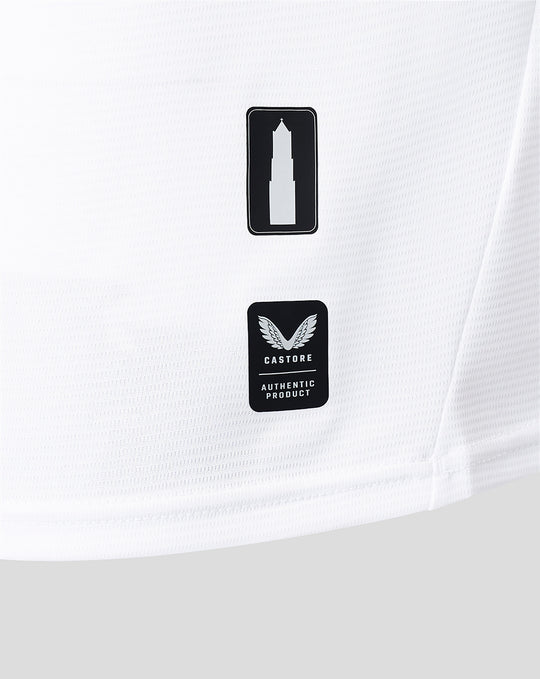 Close up of white jersey fabric showing two badges a tower icon and Castore authentic product.