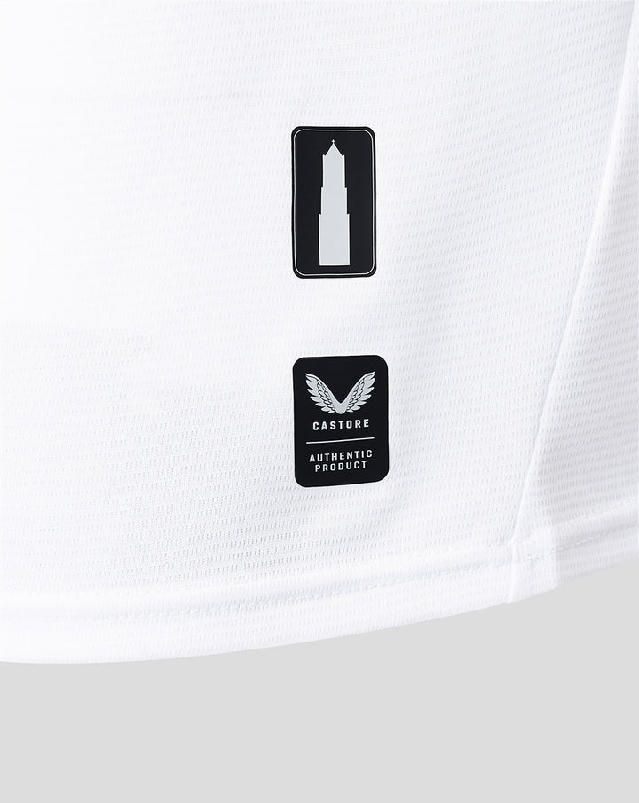 Close up of white jersey fabric showing two badges a tower icon and Castore authentic product.