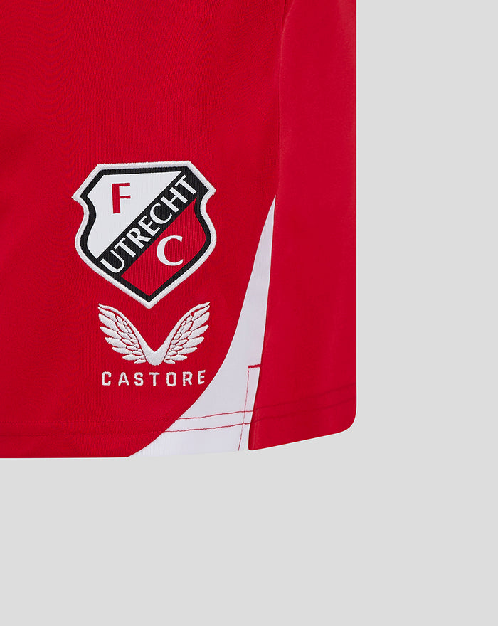 Close-up of FC Utrecht home shorts showing crest on red fabric and a white diagonal panel.