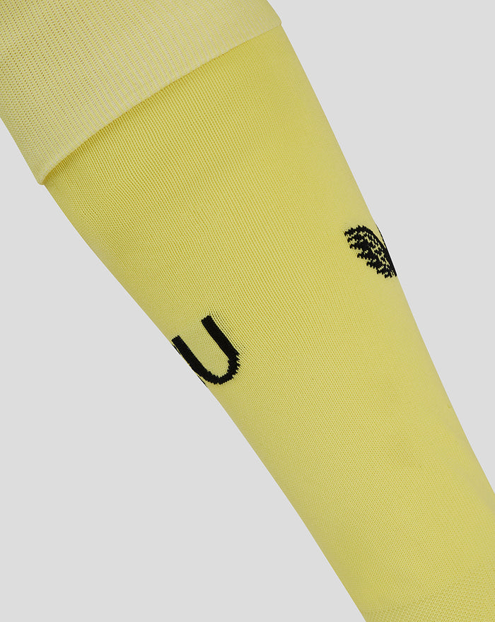 Detail van gele FC Utrecht keeper thuiskousen met zwart branding en clublogo op de kuit