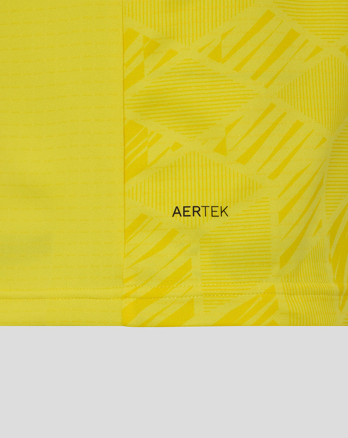 Detail van gele keepershirt stof met AerTek tekst en grafisch patroon