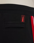 Close up of waistband and back pocket on black shorts with a small red graphic patch above the pocket