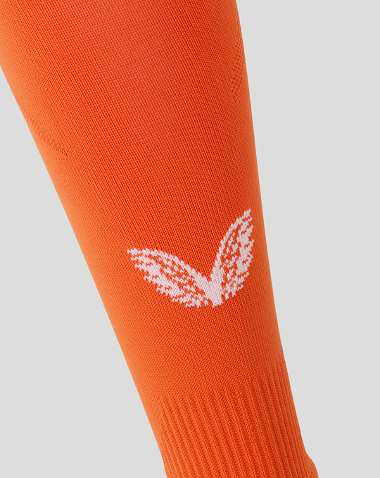 Orange goalkeeper sock close up with white logo on the lower leg