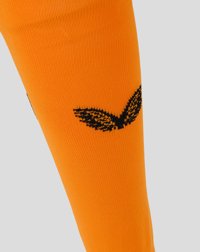 Close up of orange goalkeeper sock fabric with black geometric zigzag pattern near the cuff.