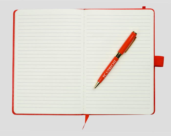 Open red FC Utrecht A5 notebook with lined pages and a red pen across the center.