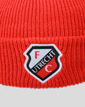Close-up of red knit beanie folded cuff featuring FC Utrecht crest patch.