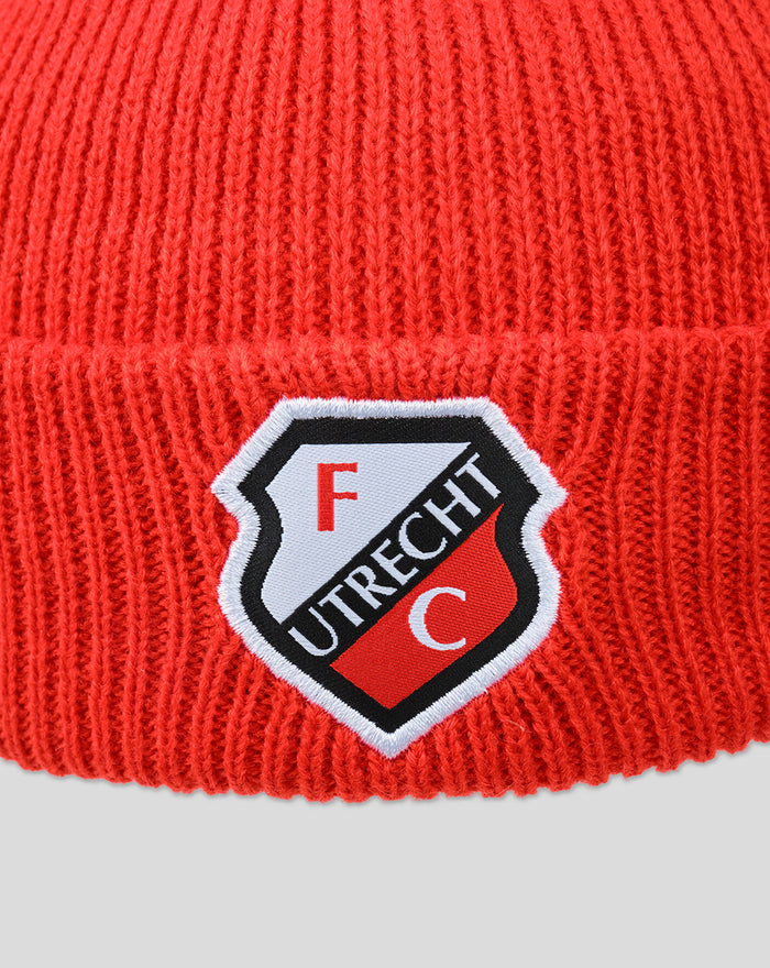 Close-up of red knit beanie folded cuff featuring FC Utrecht crest patch.